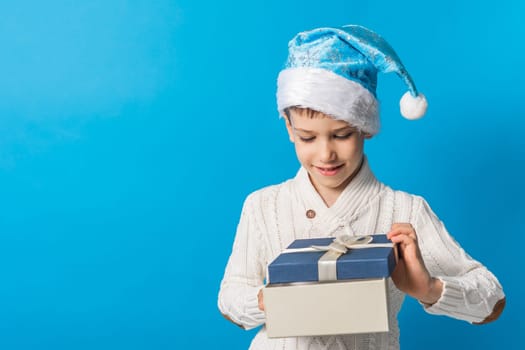 Child boy gift. Kid in blue christmas hat holds gift box. Shopping time. Banner header with copy space. Generation alpha and gen alpha