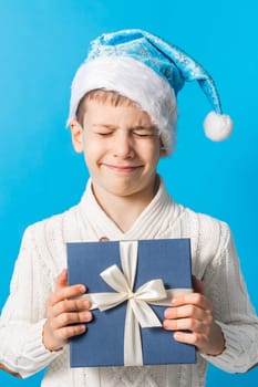Child boy gift. Kid in blue christmas hat holds gift box. Shopping time. Banner header with copy space. Generation alpha and gen alpha