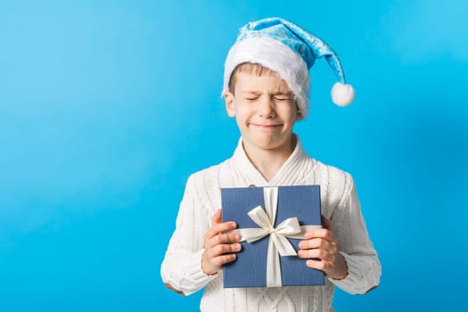 Child boy gift. Kid in blue christmas hat holds gift box. Shopping time. Banner header with copy space. Generation alpha and gen alpha