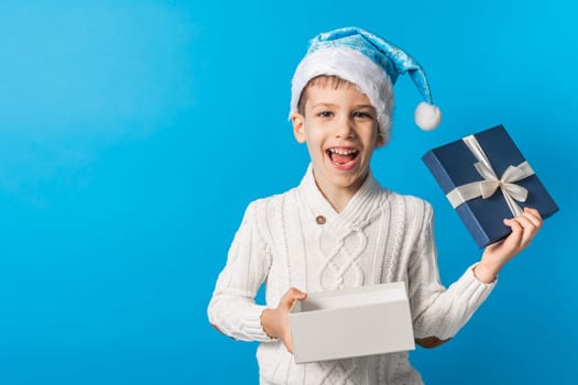 Child boy gift. Kid in blue christmas hat holds gift box. Shopping time. Banner header with copy space. Generation alpha and gen alpha