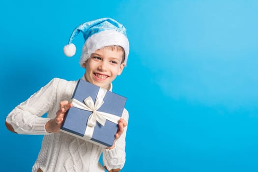 Child boy gift. Kid in blue christmas hat holds gift box. Shopping time. Banner header with copy space. Generation alpha and gen alpha
