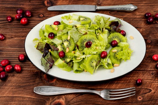 Fresh vegan salad of kiwi,mix leaves, berries and pine nuts. Close up.