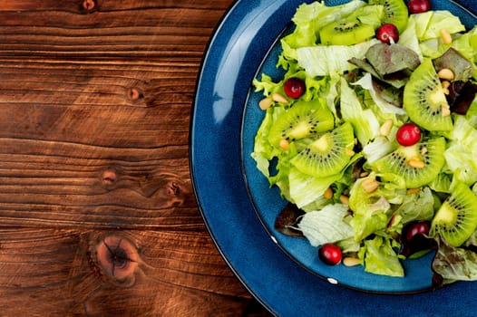 Fresh vegan salad of kiwi,mix leaves, berries and pine nuts. Close up.