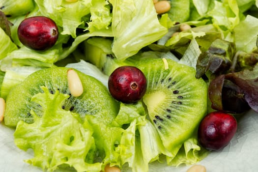 Fresh vegan salad of kiwi,mix leaves, berries and pine nuts. Close up.