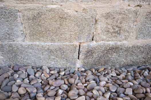 Granite ashlars wall with river pebble stones as ground. Flooring techiques for drainage