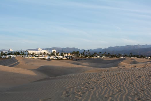 Sand dunes of Maspalomas with a view to the town of Playa del Inglés on the Canary Island of Gran Canaria, Spain, Europe. The huge sand dunes resemble a small desert and are a nature reserve.