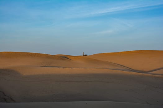 Lots of sand in the dunes of Maspalomas with the distant lighthouse on the Canary Island of Gran Canaria in Spain