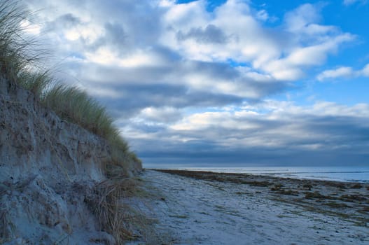 on the beach with dune on the Baltic Sea. Cloudy sky. Waves meet sand. Landscape shot from the coast