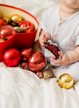 Christmas Baby in Santa Hat, Child holding christmas bauble near Present Gift Box over Holiday Lights