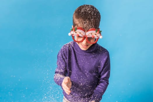 Child boy throws up on blue background. Christmas and New Year holidays concept. Generation alpha and gen alpha children. Copy space.