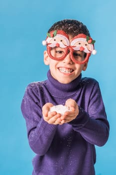 Child boy throws up on blue background. Christmas and New Year holidays concept. Generation alpha and gen alpha children. Copy space.