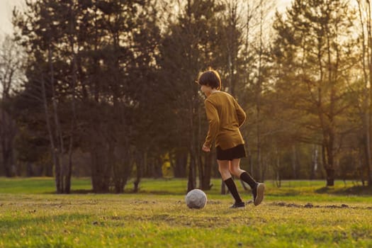 Football practice. Summer sports camp. 11-13 a teenager in sports uniform in early summer morning trains on field against background of forest . Sports and health. Children's sports sections.