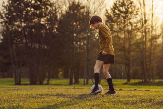 11-13 - year - old teenager in sports uniform trains on field with soccer ball in early summer morning. Sports and health. Children's sports sections. Hobbies and hobbies. Football practice.