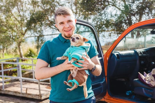 Funny portrait of a young man holding a cute chihuahua dog.