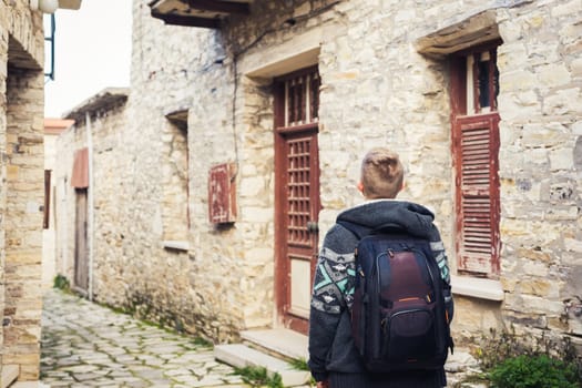 people, travel and tourism - man with backpack walking along old town street.