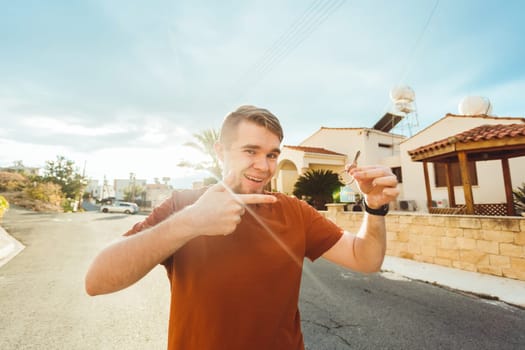 Joyful man shows keys on the background of new home.