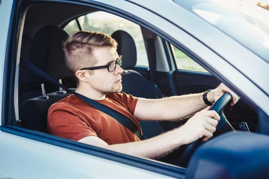 Handsome man driving his car. Happy owner. Handsome man sitting relaxed in his newly bought car looking out the window