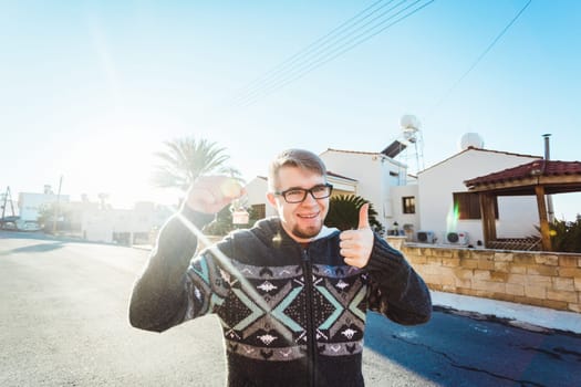 Joyful man shows keys on the background of new home.