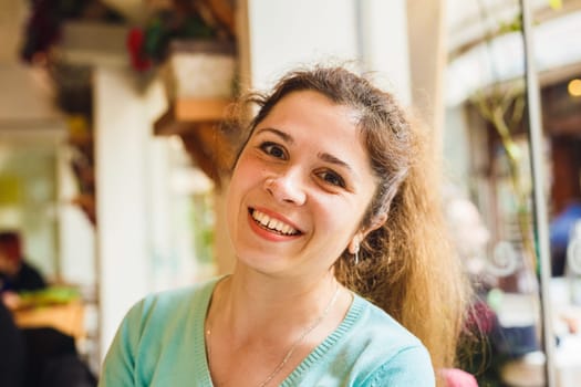 Portrait of a cute blonde smiling woman sitting in a cafe.