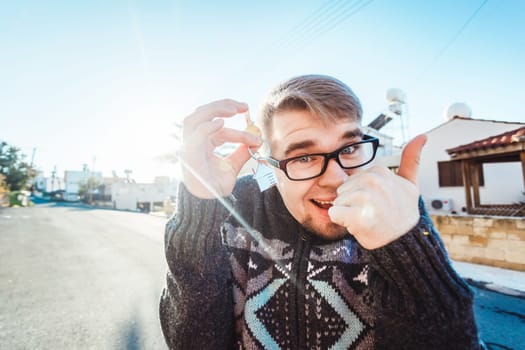 Portrait of a young man holding out new house key while gesturing thumbs up
