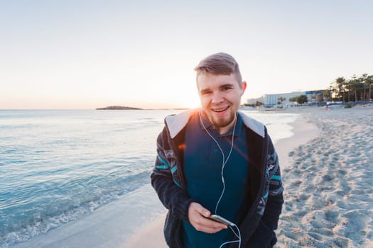 Young man enjoying the music on white sandy beach. Happy tourist relaxing on summer tropical vacation.