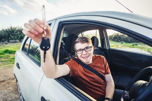 Attractive young man showing his new car keys and smiling.
