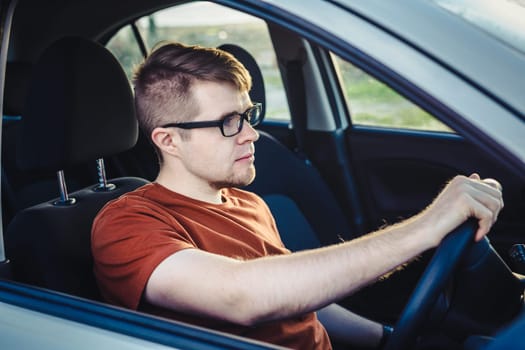 Attractive young man driving his new car.