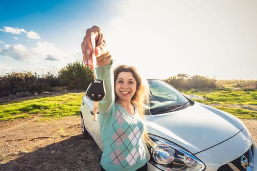 happy woman driver hold car keys near her new car.