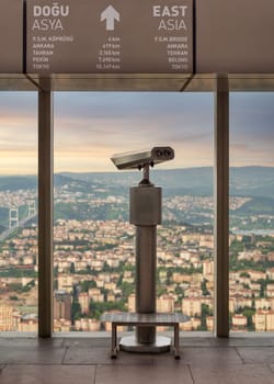Tower Optical coin-operated binocular on the observation deck of Istanbul Sapphire,Turkey, against cityscape before sunset with sign including distances to some Asian capital cities to the east