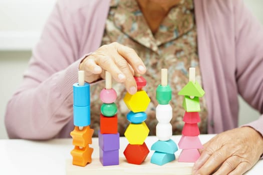 Asian elderly woman playing puzzles game for treatment dementia prevention and Alzheimer disease.