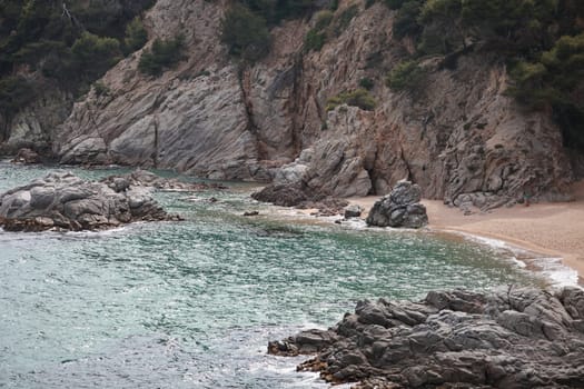 turquoise water of a sea bay near a steep rocky coast, deserted sandy beach, marine landscape