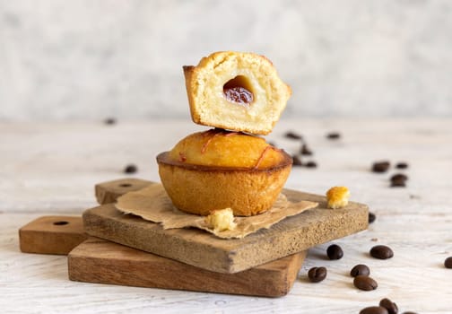 Pasticciotto leccese pastry filled with egg custard cream and sour cherry jam. Pieces of pasticiotto on a wooden board, typical apulian breakfast, close up. Table decorated with coffee beans