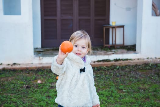 Little girl holding apples in the garden