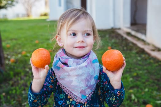 Little girl holding apples in the garden