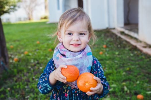 Little girl holding apples in the garden