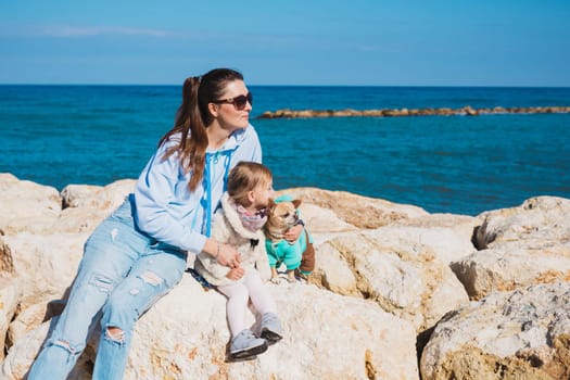 Back view of mother and her little daughter looking at the sea