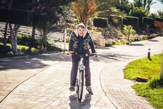 Ready to ride. Handsome young man on bicycle looking at camera and smiling while standing outdoors.