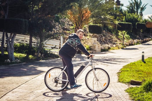 Ready to ride. Handsome young man on bicycle looking at camera and smiling while standing outdoors.