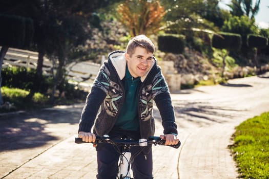Ready to ride. Handsome young man on bicycle looking at camera and smiling while standing outdoors.