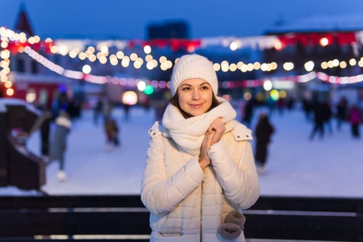 Happy young woman in winter on the ice rink taking picture on smartphone.