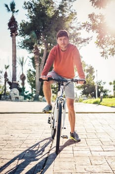 Portrait of handsome guy riding bicycle in the park.