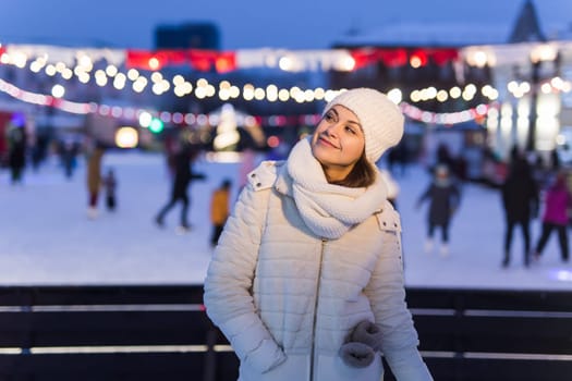Christmas, winter, technology and leisure concept - happy young woman taking picture with smartphone on ice skating rink.