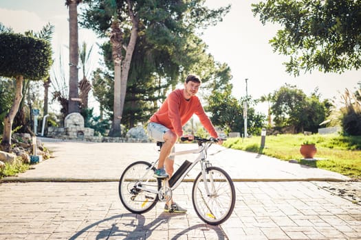 Portrait of handsome guy riding bicycle in the park.