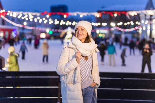 Christmas, winter, technology and leisure concept - happy young woman taking picture with smartphone on ice skating rink.