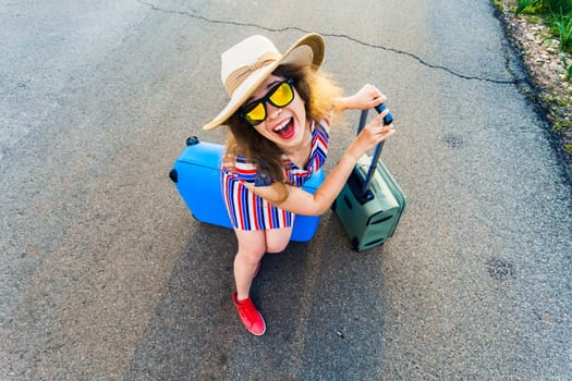 Happy laughing young woman with suitcases on the road
