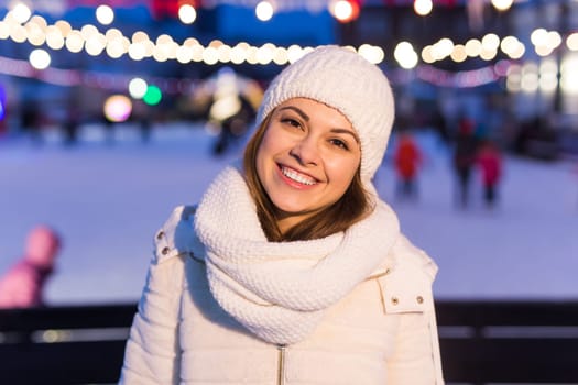 Happy young woman in winter on the ice rink taking picture on smartphone.