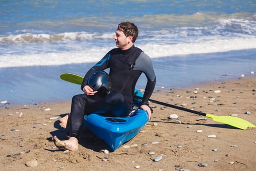 Man with kayak on the beach in sunny day.
