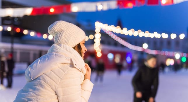 Happy young woman in winter on the ice rink taking picture on smartphone.