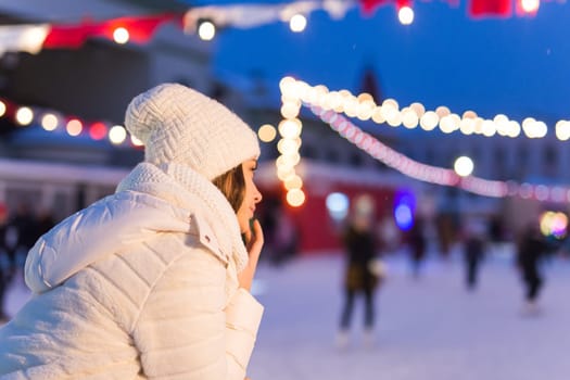 Christmas, winter, technology and leisure concept - happy young woman taking picture with smartphone on ice skating rink.