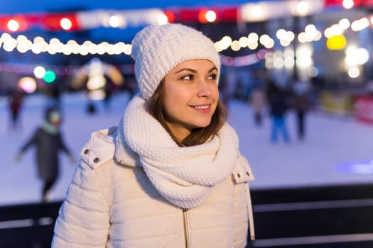Christmas, winter, technology and leisure concept - happy young woman taking picture with smartphone on ice skating rink.